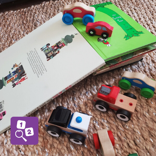 Books used to make a ramp, surrounded by 6 toy cars.