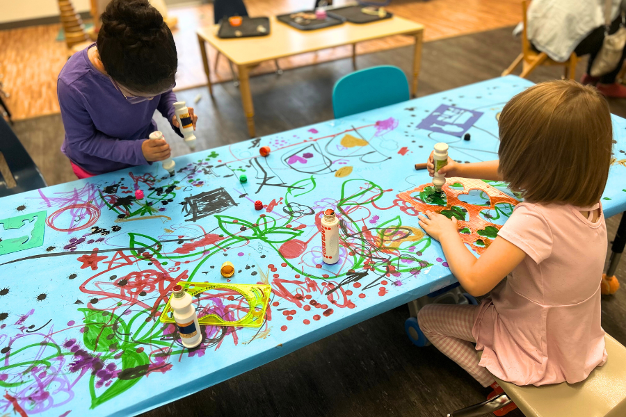 Preschool kids play with building bricks in while sitting on floor in daycare