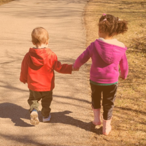 Toddlers holding hands while walking outside