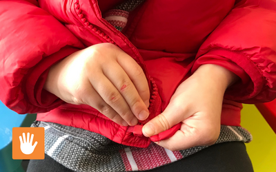 Infant learning how to zip up a zipper jacket.