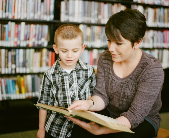 a woman reads a book to a young boy.
